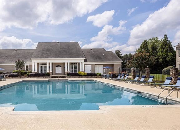 a pool with chairs around it in front of a house at Bedford Parke Apartments, Georgia