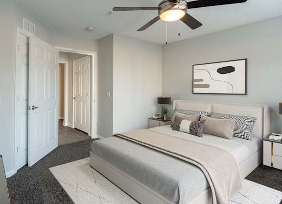 A bedroom with a large bed and a ceiling fan.