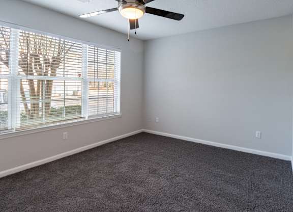 A room with a ceiling fan and a window with blinds.