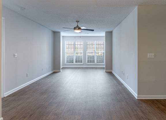 A spacious room with a ceiling fan and a sliding glass door.