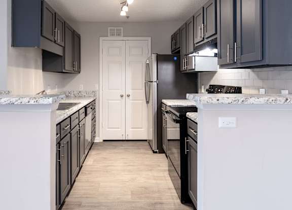 A kitchen with black cabinets and a white door.