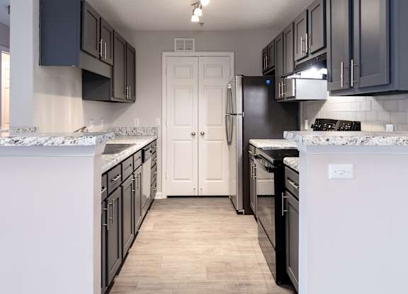 A kitchen with black cabinets and a white door.