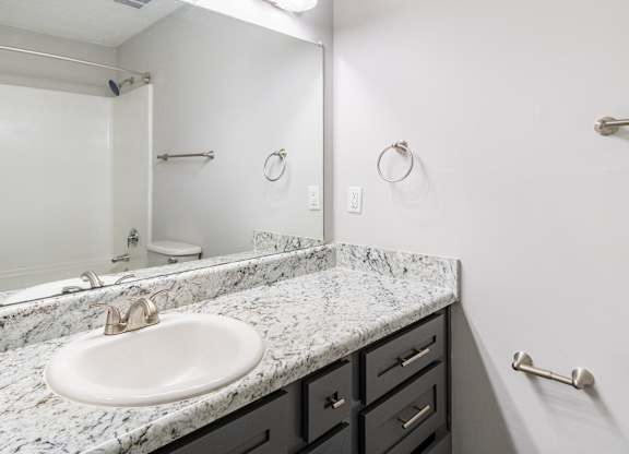 A bathroom with a marble countertop and a white sink.