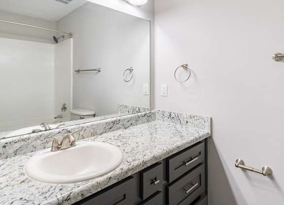 A bathroom with a marble countertop and a white sink.