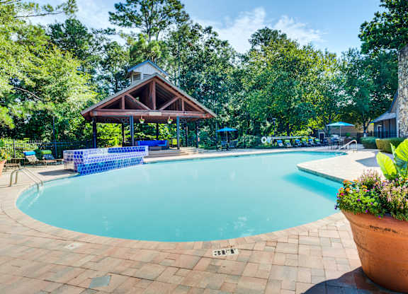A pool surrounded by trees and a pavilion.