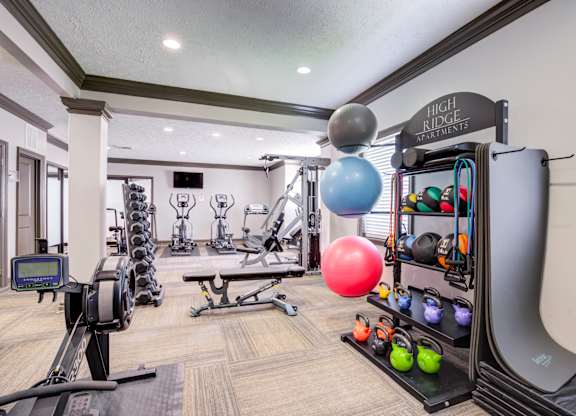 A gym with a variety of equipment including weights, exercise balls, and resistance bands.
