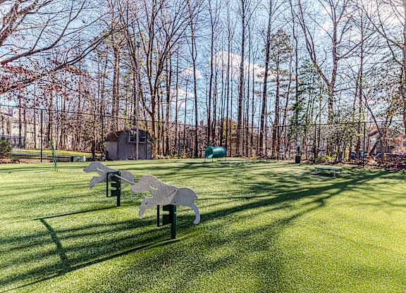 A park with a horse sculpture in the middle of a grassy area.
