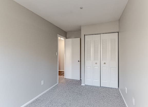 A room with a white door and a grey carpet.