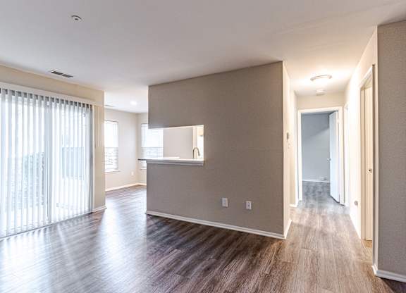 A spacious room with wooden floors and a large window with white curtains.