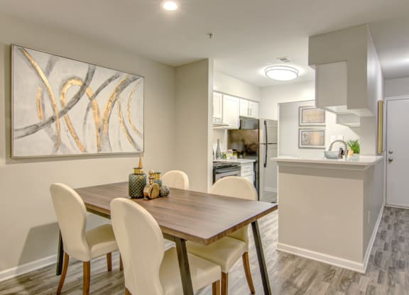 a dining area with a wooden table and white chairs at Hunters Chase Apartments, Virginia