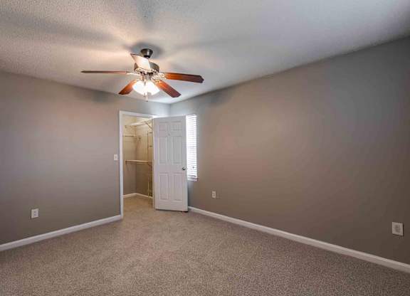A room with a ceiling fan and carpeted floor.