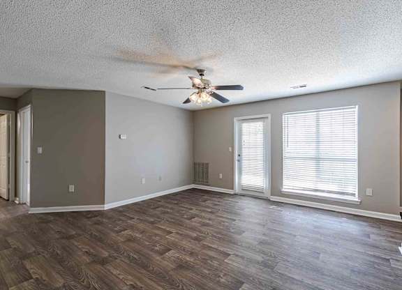 A room with a ceiling fan and wooden flooring.