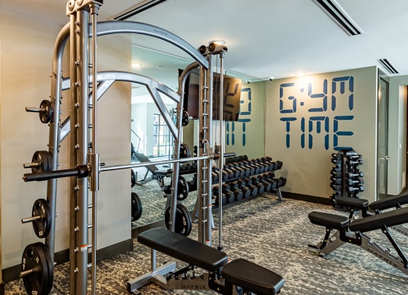 a gym with weights and cardio equipment in a hotel room at The Louis Apartment Flats, Louisville, KY