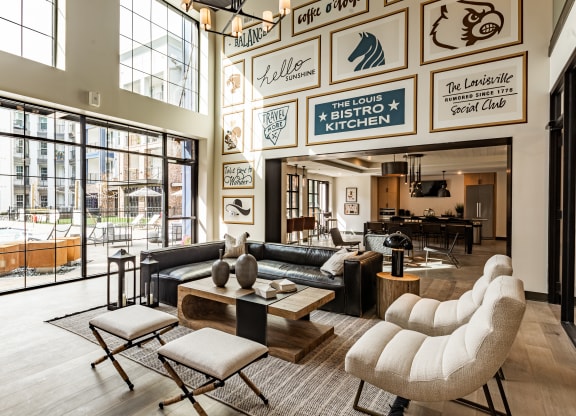 a living room with couches and tables and large windows at The Louis Apartment Flats, Louisville, KY