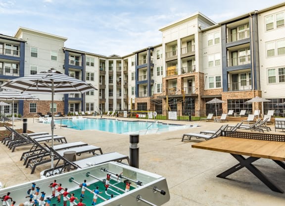 an outdoor pool with tables and chairs and an apartment building at The Louis Apartment Flats, Louisville