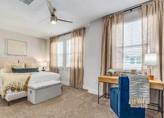 A bedroom with a bed, a chair, and a table.