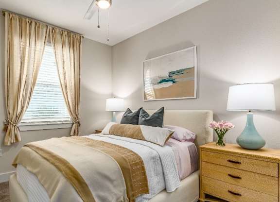A bedroom with a bed, nightstand, and a painting on the wall.