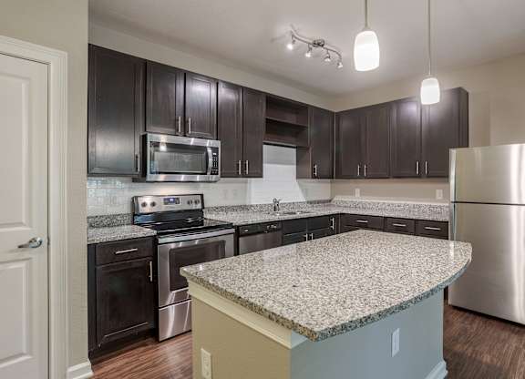 A kitchen with a granite countertop and stainless steel appliances.