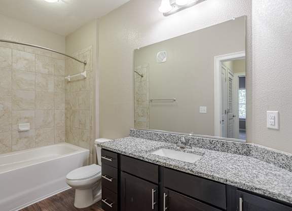 A bathroom with a marble countertop and a white bathtub.