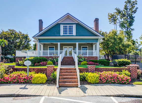 A blue house with a white porch and a brick staircase leading to the front door.