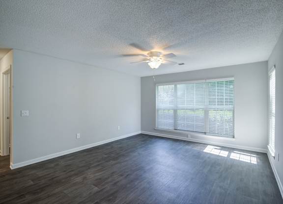 A room with a ceiling fan and a window with blinds.