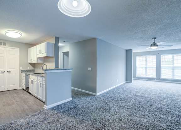 A spacious kitchen and living room with a ceiling fan.