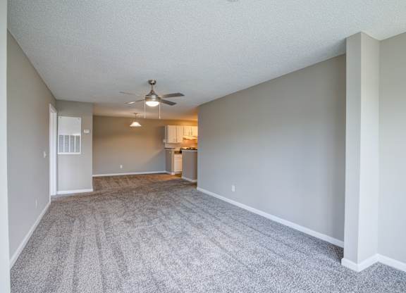 A spacious room with a ceiling fan and carpeted floor.