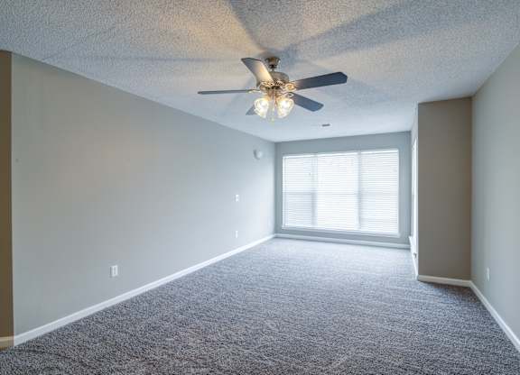 A room with a ceiling fan and carpeted floor.