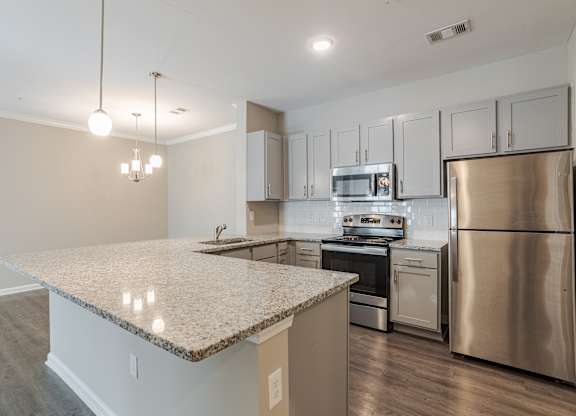A kitchen with a granite countertop and stainless steel appliances.