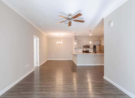 A spacious room with a ceiling fan and hardwood floors.
