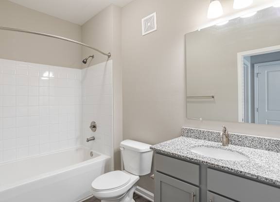 A white toilet sits next to a white bathtub in a bathroom.
