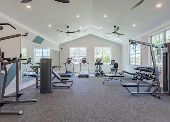 A spacious gym with a variety of equipment including treadmills, elliptical machines, and weight machines.