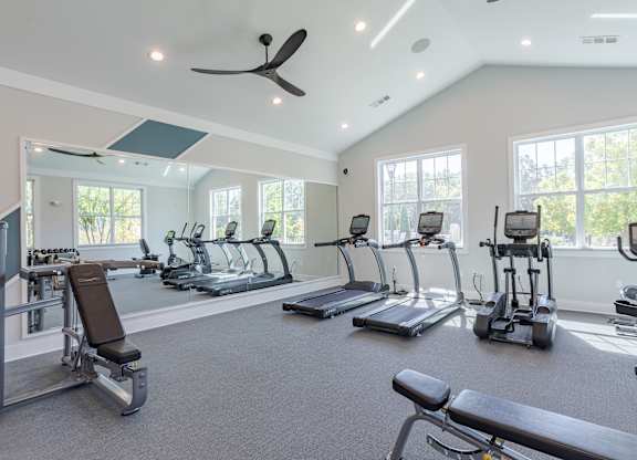 A spacious gym with a variety of exercise equipment and a ceiling fan.