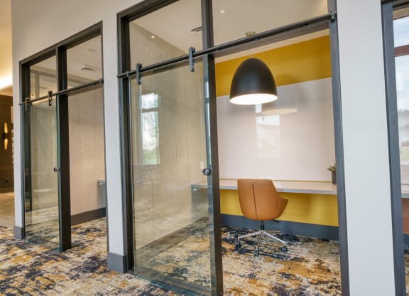 a conference room with a yellow accent wall and glass sliding doors