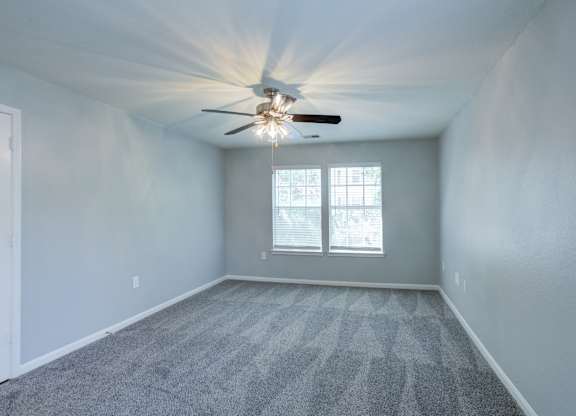 A room with a ceiling fan and carpeted floor.
