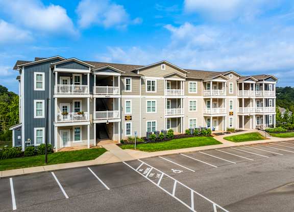 A large apartment complex with a parking lot in front.