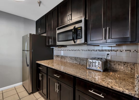 a kitchen with dark cabinets and granite countertops at Misty Ridge Apartments, Woodbridge, VA 22191