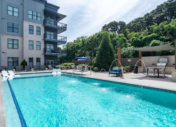 A large swimming pool in front of a multi-story apartment building.