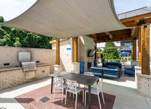 A patio with a table and chairs under a shade sail.