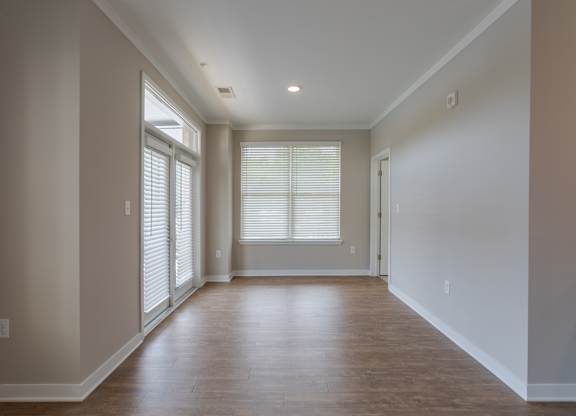 A room with wooden floors and a window with blinds.