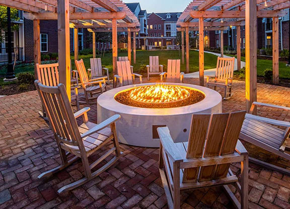 a fire pit in the middle of a brick patio with wooden chairs and a pergola at Canopy at Ginter Park Apartments, Richmond, VA, 23227