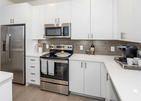 a kitchen with a stove top oven next to a refrigerator at Canopy at Ginter Park Apartments in Richmond, 23227