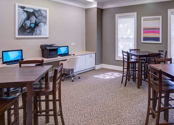 A room with a dining table and chairs, a computer desk with two monitors, and a bookshelf at Austin Chase Apartments, Macon, Georgia