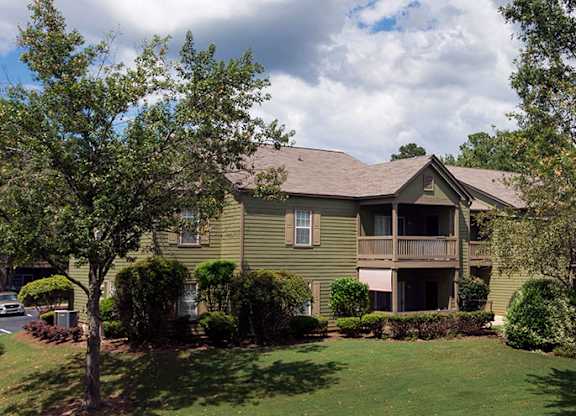 A green house with a brown roof and a balcony at Austin Chase Apartments, Macon, 31210