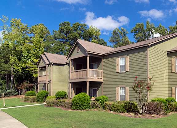 A green two story apartment building with a balcony on the second floor at Austin Chase Apartments, Macon, Georgia