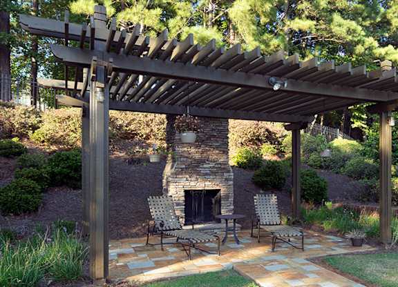 A patio with a fireplace and chairs under a wooden pergola at Austin Chase Apartments, Macon, GA