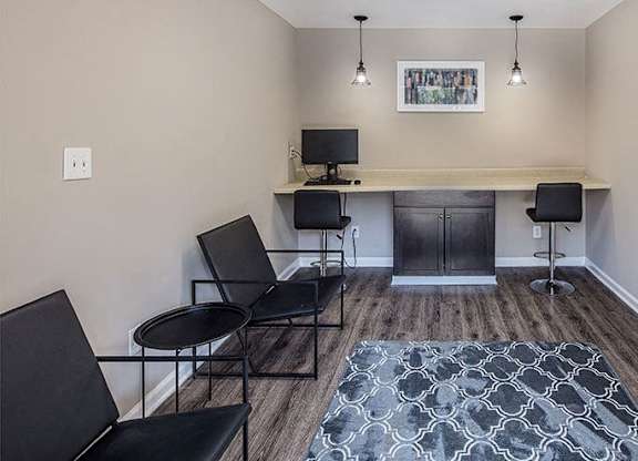 A room with a desk, chairs, and a rug.