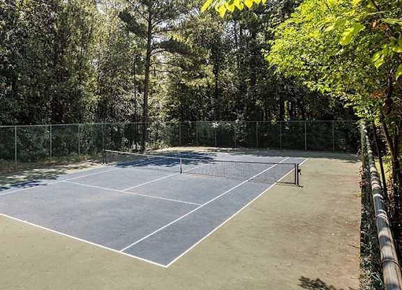 A tennis court surrounded by a fence and trees.