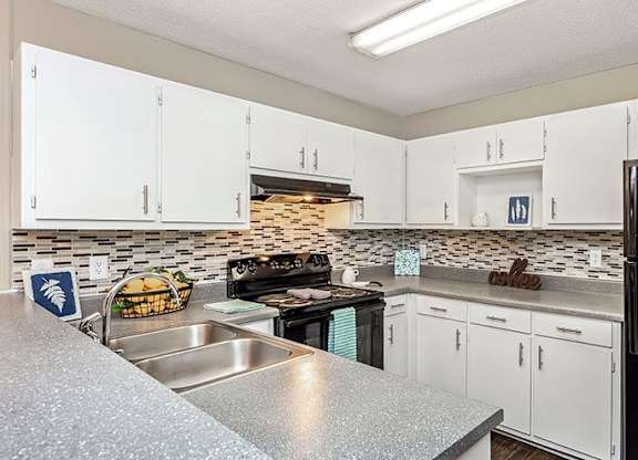A kitchen with white cabinets and a black refrigerator.