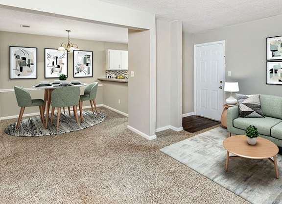 A living room with a green couch and a dining table with chairs.